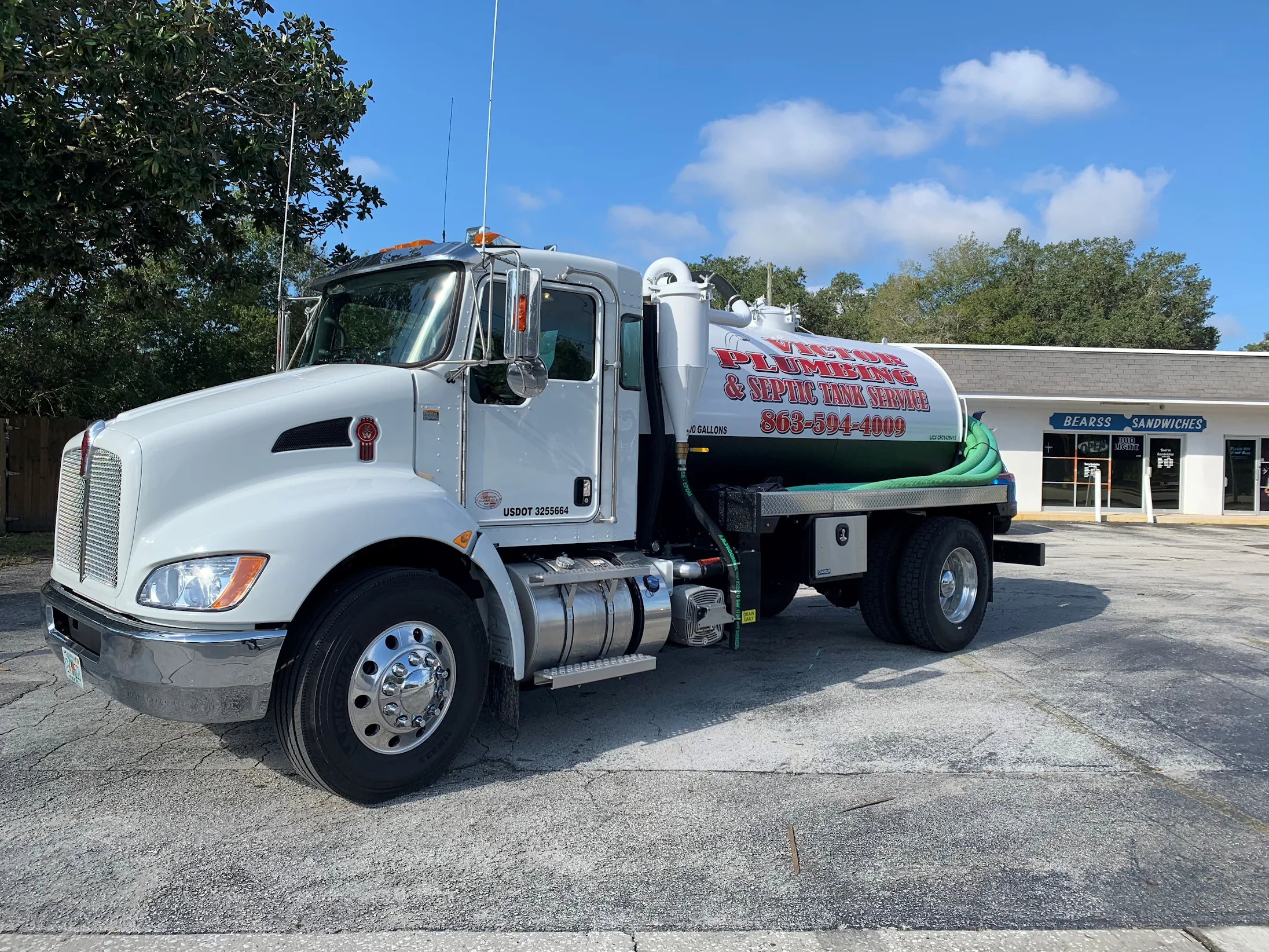 A white Victor Plumbing truck parked in front of a building.