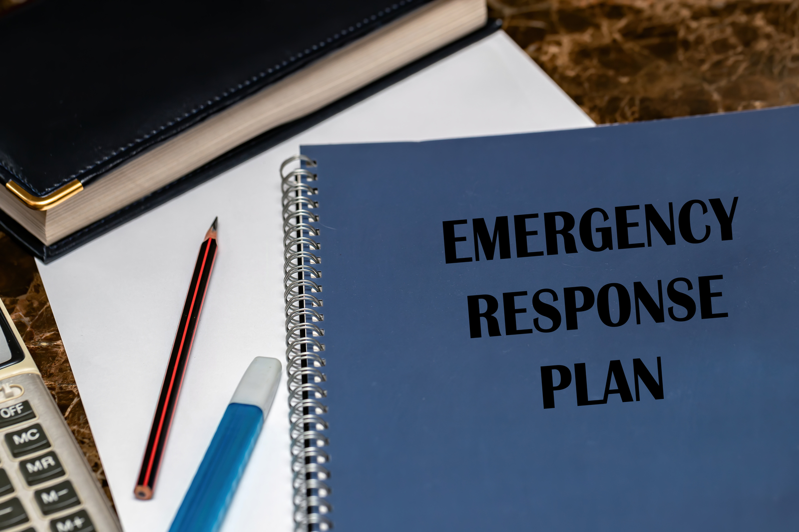 An emergency response plan on a desk with a calculator for Victor Plumbing.