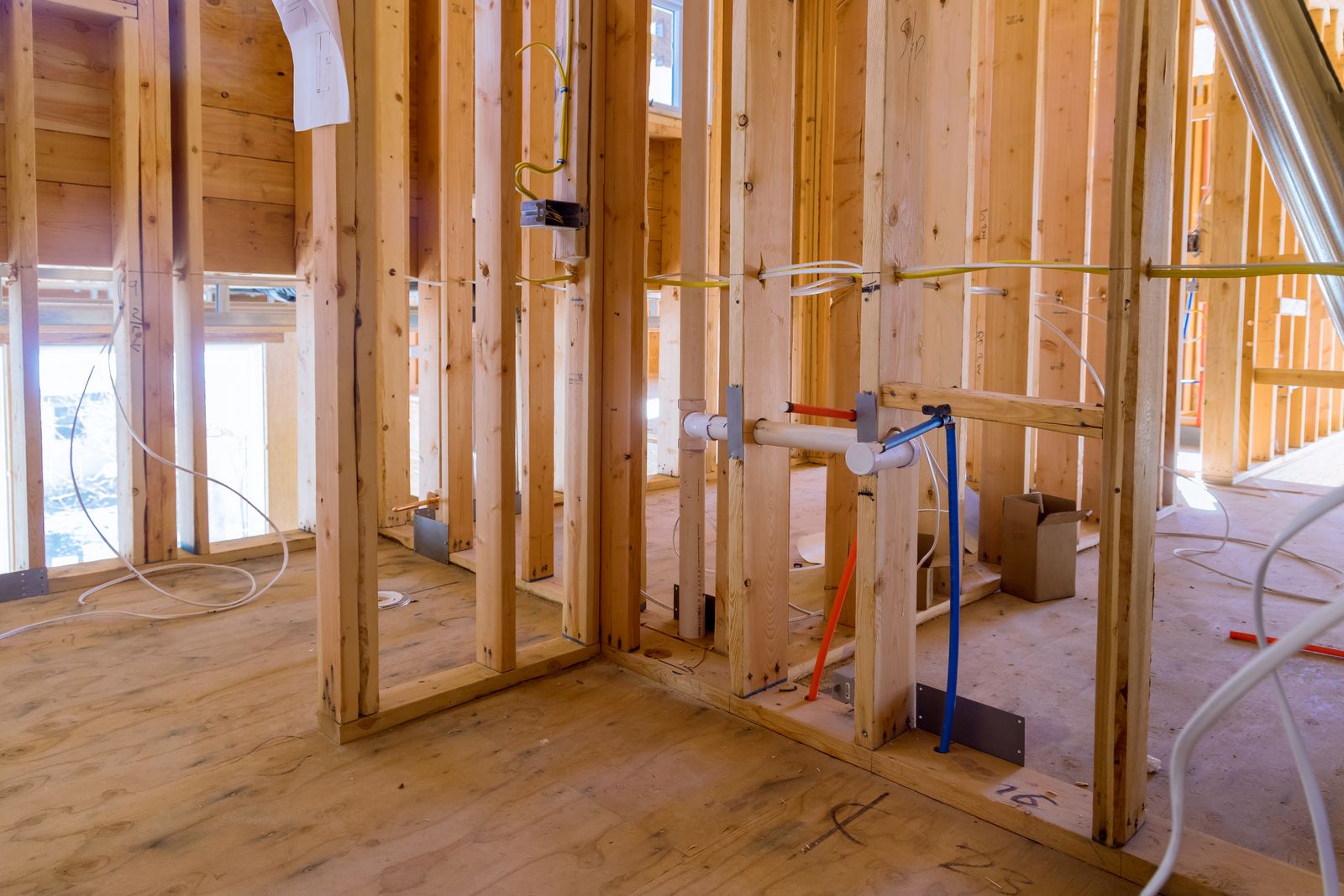 An unfinished room with wood framing and pipes, undergoing construction for Victor Plumbing.