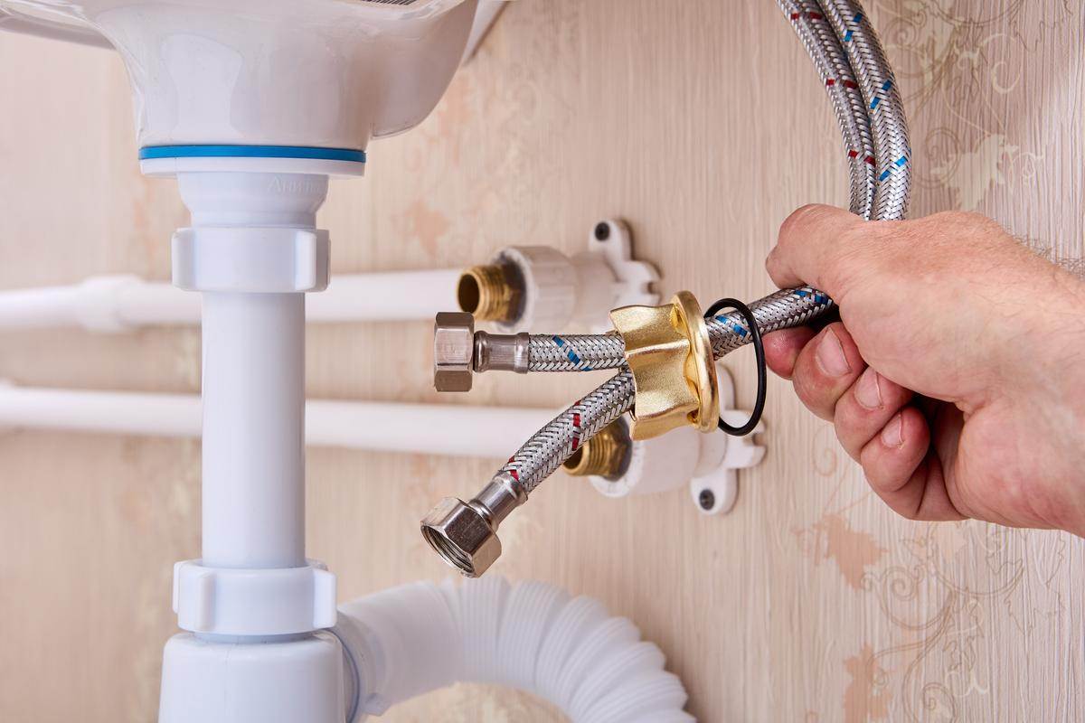 A Victor plumber fixing a sink with a hose.