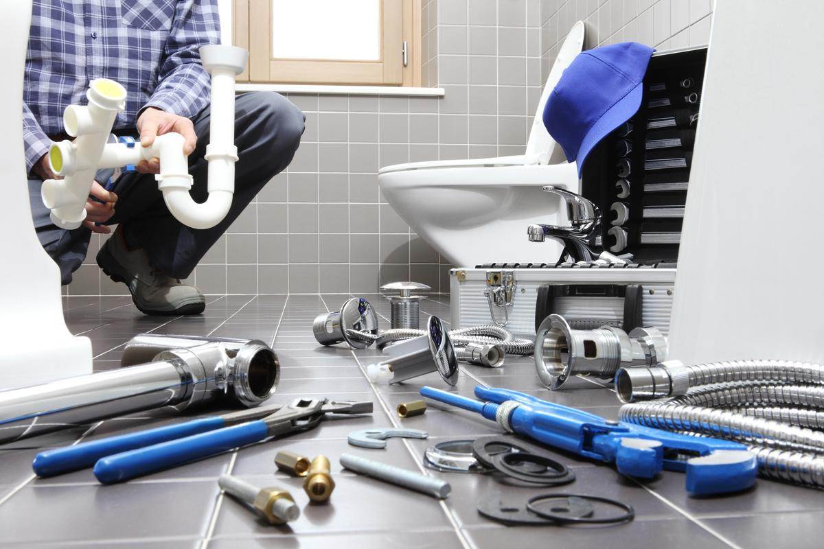 A man, identified as Victor, is diligently working on a toilet with plumbing tools.