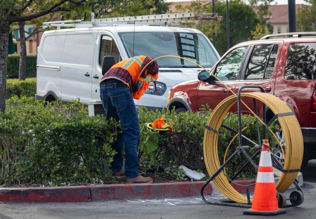 Victor, a plumber, is working on a cable in a parking lot.