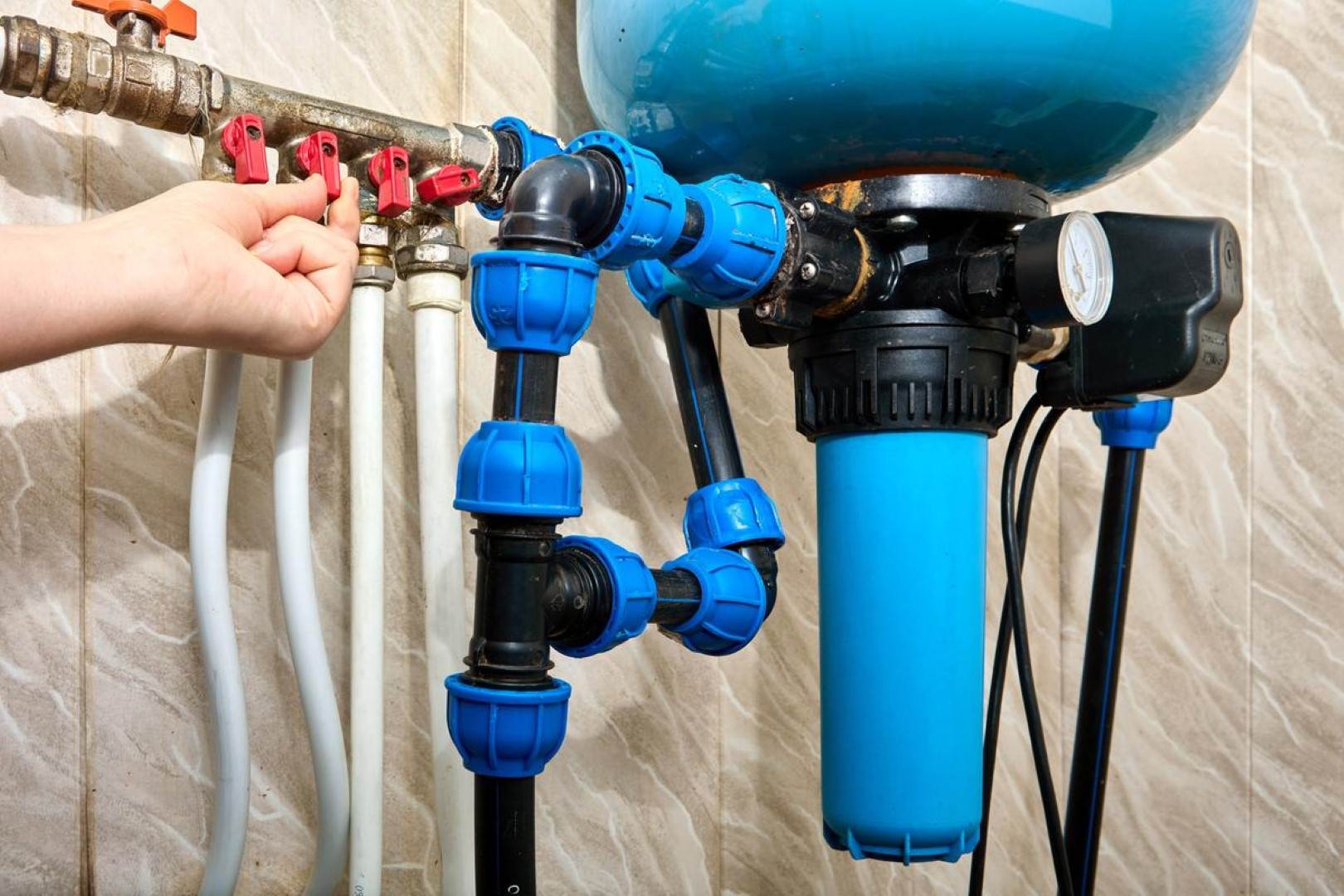 A person is holding a blue water tank and hoses for Victor Plumbing's septic system.