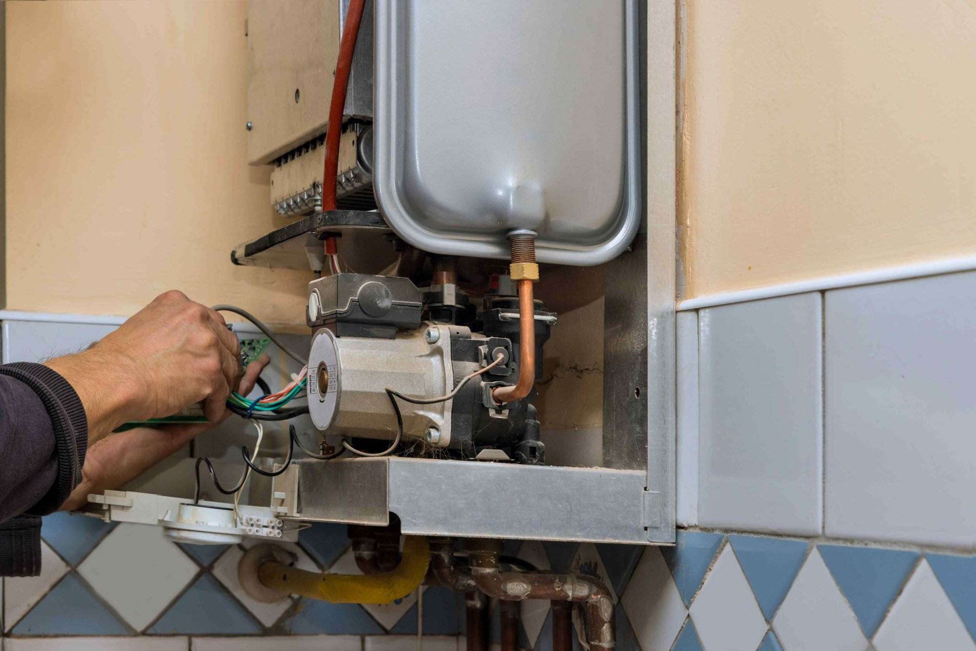 A man from Victor Plumbing fixing a water heater in a bathroom.
